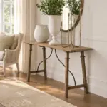 Alba Oak Console Table in natural timber with a slender rectangular top and elegant curved metal detailing, styled in a warm, neutral interior.