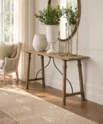Alba Oak Console Table in natural timber with a slender rectangular top and elegant curved metal detailing, styled in a warm, neutral interior.