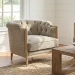 Coventry Button Chair featuring a button-tufted back, curved arms, neutral linen-blend upholstery and exposed elmwood frame in a light-filled living room.