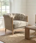 Coventry Button Chair featuring a button-tufted back, curved arms, neutral linen-blend upholstery and exposed elmwood frame in a light-filled living room.