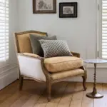 Harvey Leather Armchair in brown leather with carved natural ashwood frame, antique brass stud detailing and cotton canvas sides, styled in a classic living room.