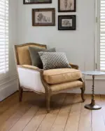 Harvey Leather Armchair in brown leather with carved natural ashwood frame, antique brass stud detailing and cotton canvas sides, styled in a classic living room.